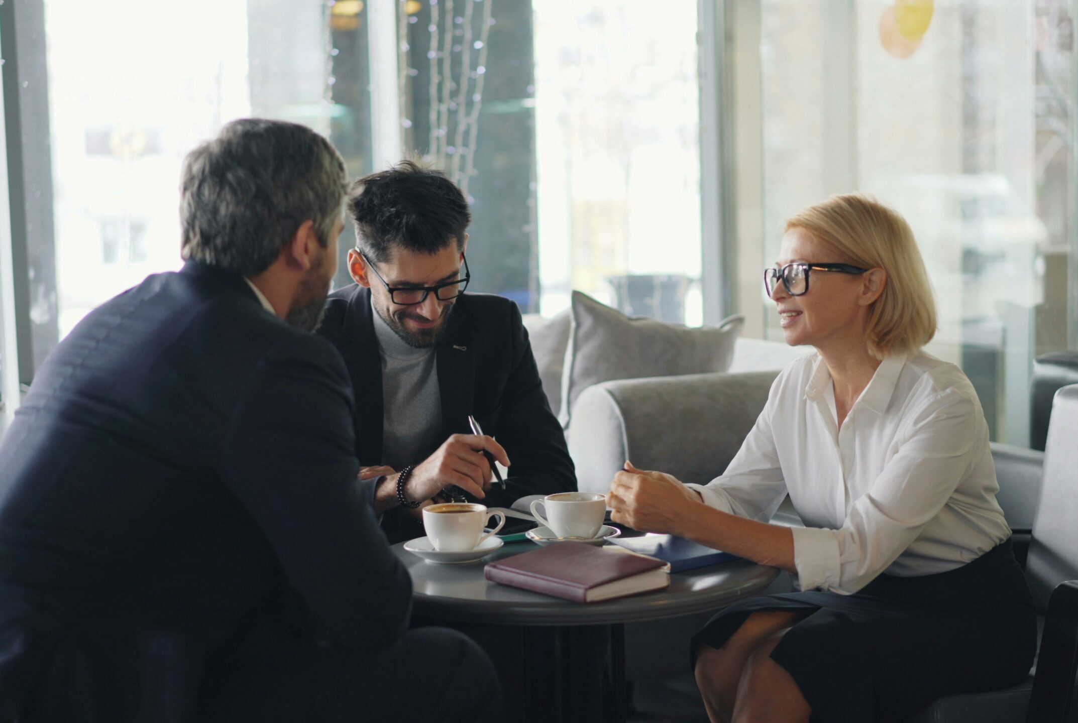 A woman and two men sitting around a table in a professional setting.