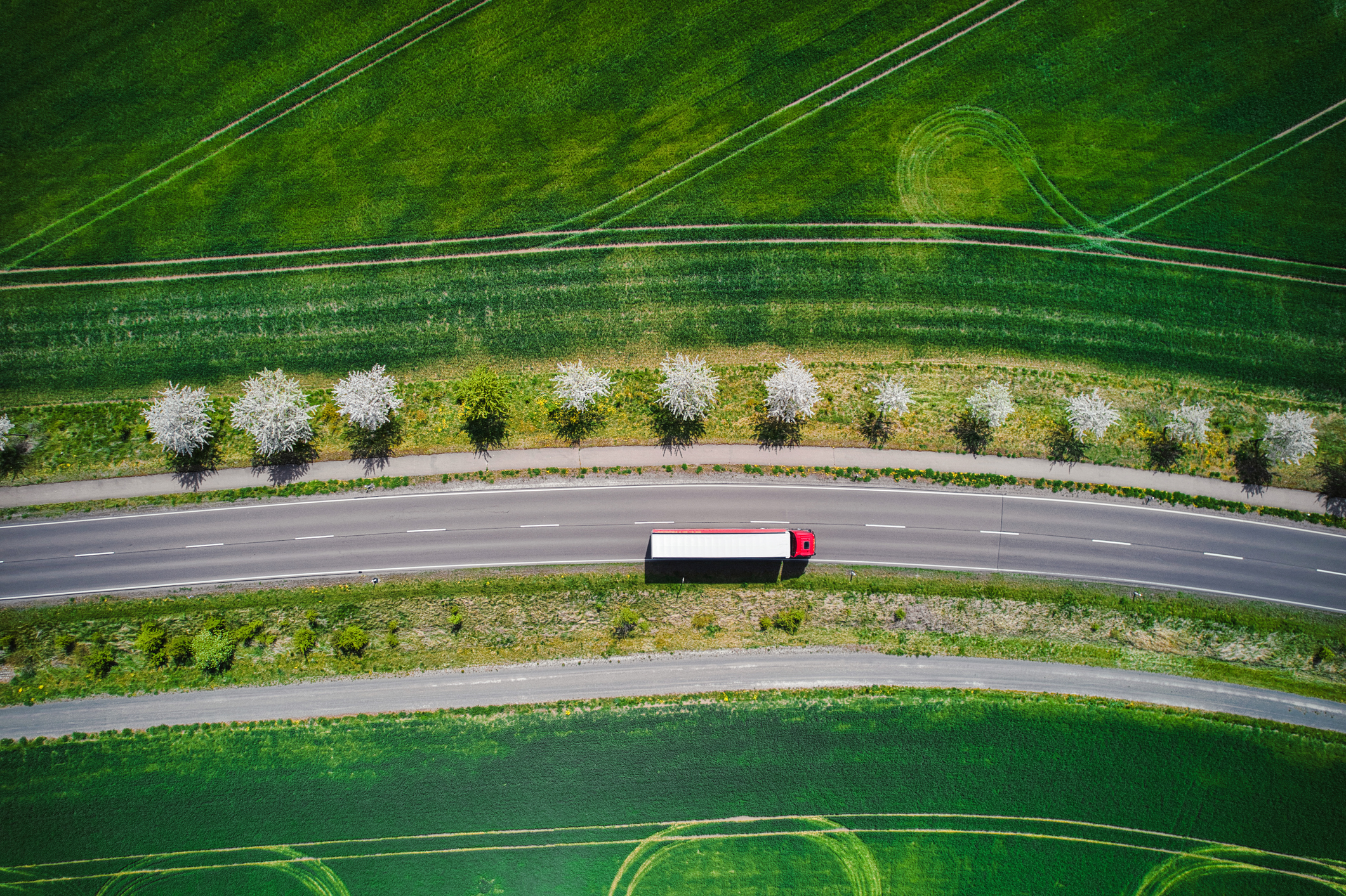 Drone shot direct above a truck moves along a single road.